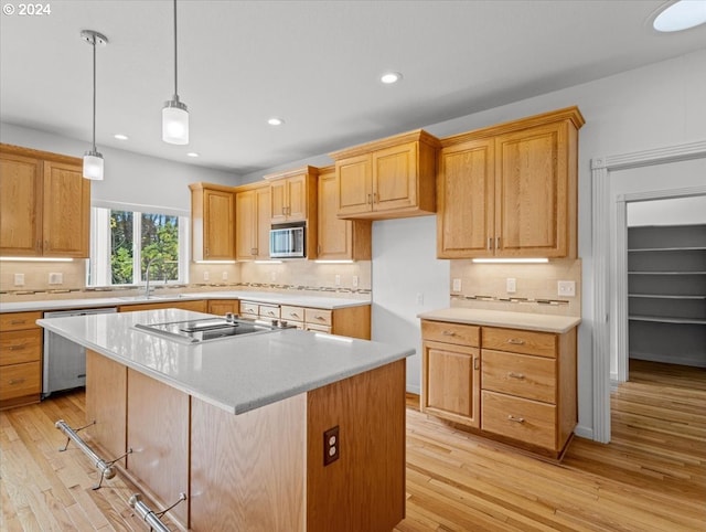 kitchen with backsplash, stainless steel appliances, light wood-type flooring, and a kitchen island