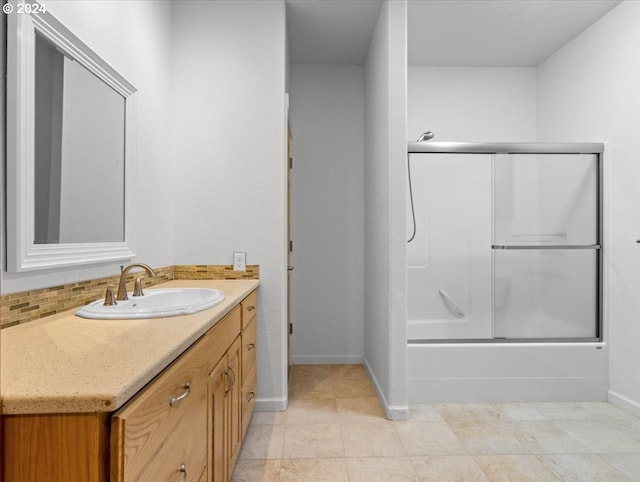 bathroom featuring vanity, enclosed tub / shower combo, tile patterned floors, and backsplash