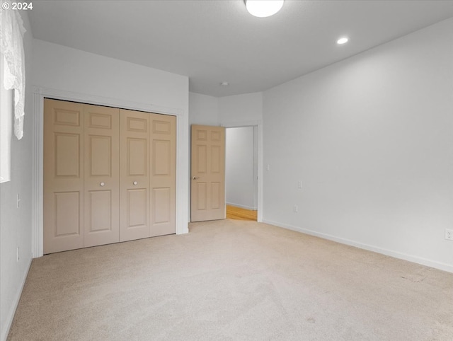 unfurnished bedroom featuring light colored carpet and a closet