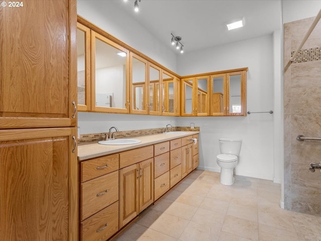 bathroom with vanity, tiled shower, toilet, and tile patterned floors