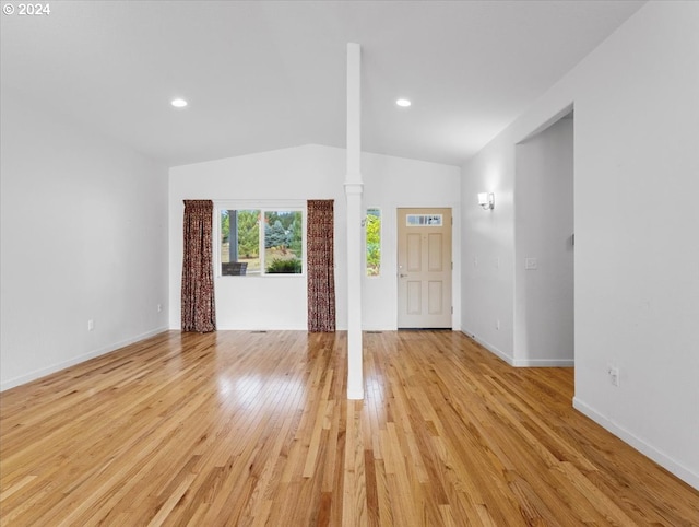 foyer entrance featuring ornate columns, light hardwood / wood-style floors, and vaulted ceiling