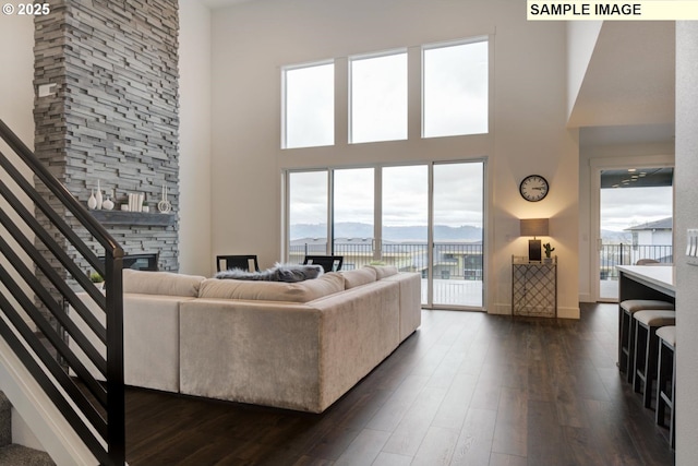 1004 S Mountain Pl, Ridgefield, WA 98642 - living area featuring a stone fireplace, a towering ceiling, stairs, dark wood finished floors, and plenty of natural light