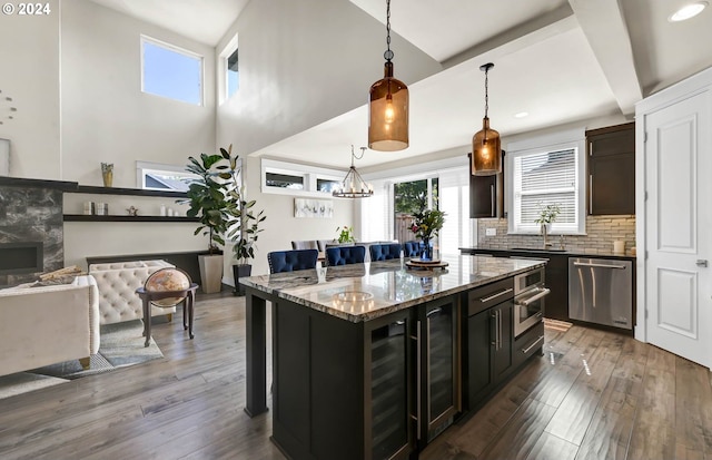 kitchen featuring a kitchen island, dark hardwood / wood-style flooring, stainless steel appliances, light stone countertops, and hanging light fixtures