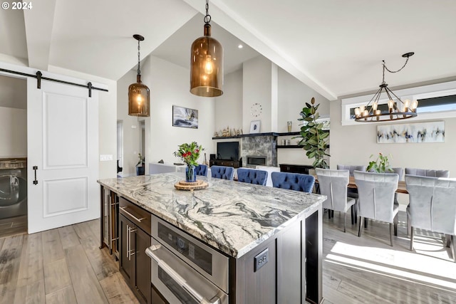 kitchen with pendant lighting, a barn door, washer / clothes dryer, and light hardwood / wood-style flooring