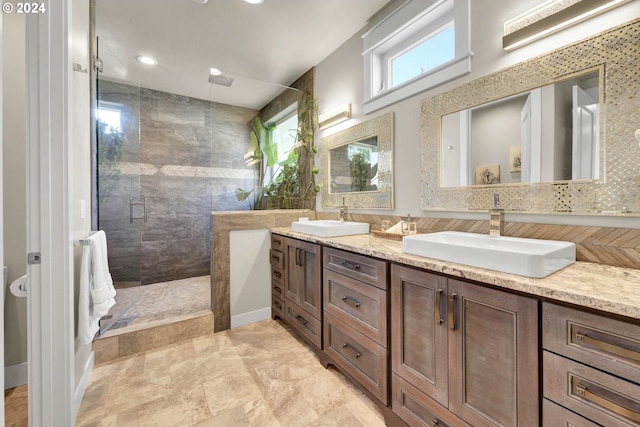 bathroom with a healthy amount of sunlight, tiled shower, and vanity