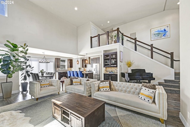 living room with dark wood-type flooring, high vaulted ceiling, and a notable chandelier