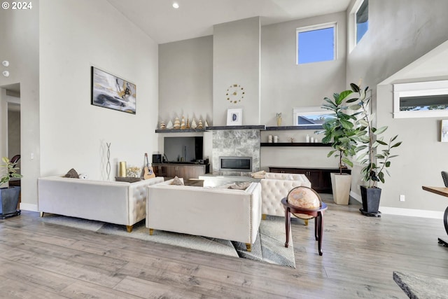 living room featuring a fireplace, a towering ceiling, and light hardwood / wood-style floors