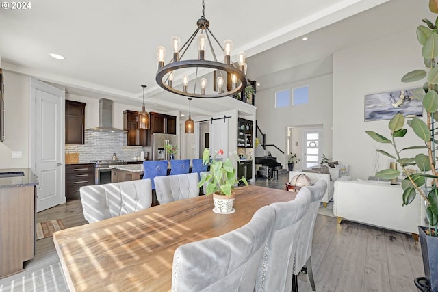 dining area featuring an inviting chandelier, a barn door, light hardwood / wood-style floors, and sink