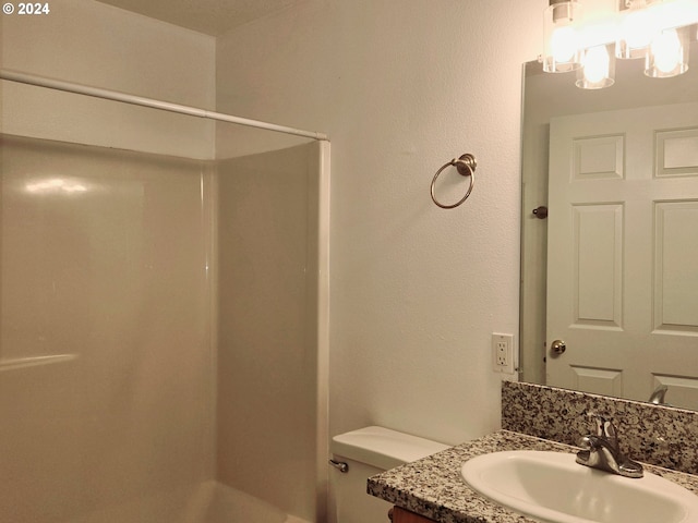 bathroom featuring a shower, vanity, and toilet