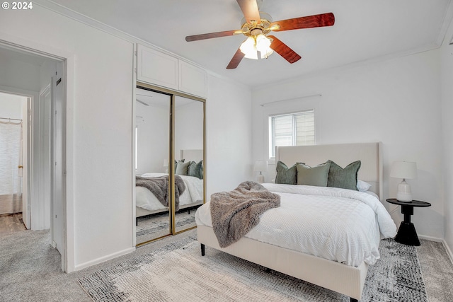 bedroom with ornamental molding, a closet, light colored carpet, and ceiling fan