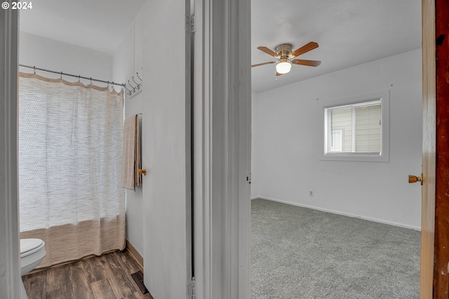 bathroom featuring ceiling fan, hardwood / wood-style flooring, walk in shower, and toilet