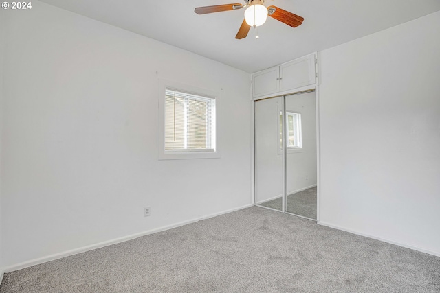 unfurnished bedroom featuring light carpet, a closet, multiple windows, and ceiling fan