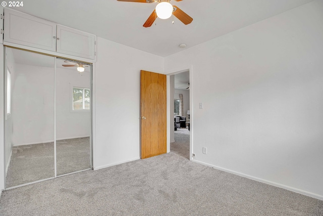 unfurnished bedroom featuring light carpet, ceiling fan, and a closet