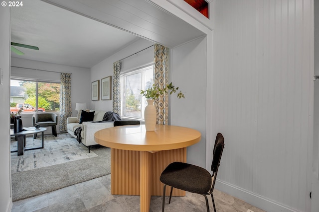 dining room featuring wooden walls, ceiling fan, and light colored carpet