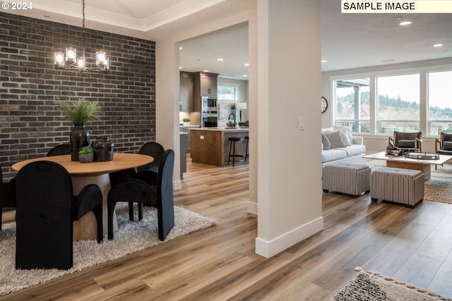 dining space with hardwood / wood-style flooring, an inviting chandelier, and brick wall