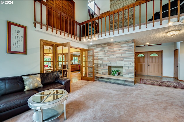 carpeted living room featuring french doors, a towering ceiling, a textured ceiling, and a stone fireplace