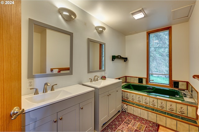 bathroom featuring a relaxing tiled tub, vanity, and a wealth of natural light