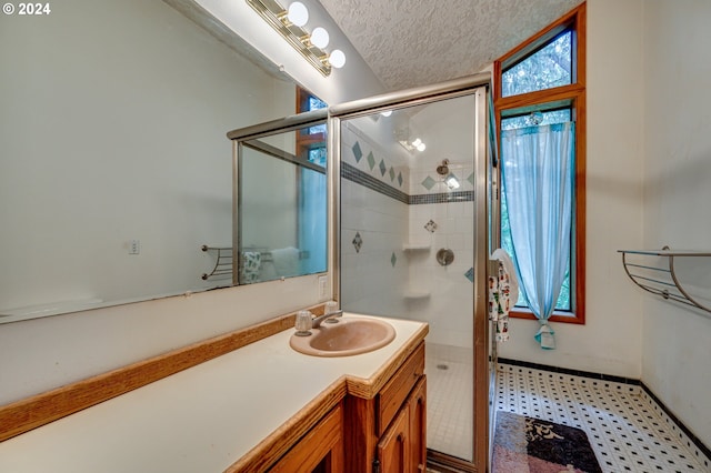 bathroom with vanity, a shower with door, and a textured ceiling