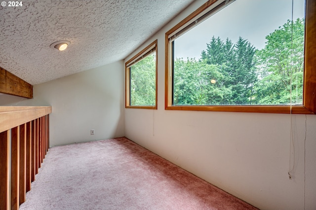 carpeted empty room with a textured ceiling and vaulted ceiling