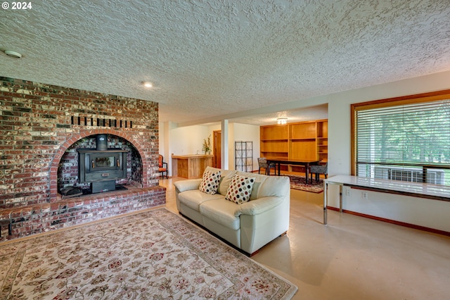 living room featuring a wood stove, a textured ceiling, and concrete floors