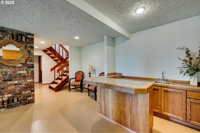 bar featuring a textured ceiling and sink