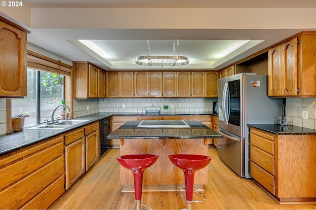 kitchen featuring a center island, sink, a raised ceiling, light hardwood / wood-style flooring, and a kitchen bar