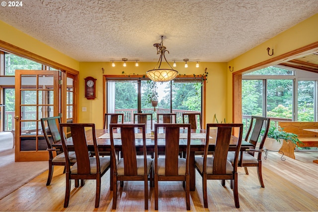 dining area with hardwood / wood-style floors, rail lighting, and a textured ceiling