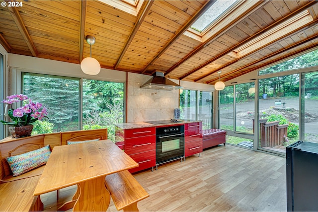 kitchen with black appliances, wall chimney range hood, and a wealth of natural light