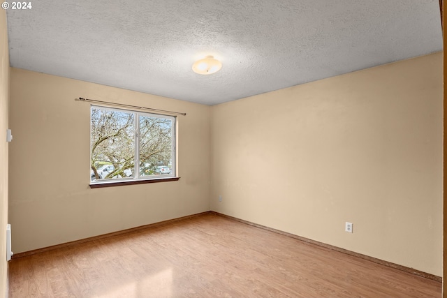 spare room with a textured ceiling and light hardwood / wood-style floors