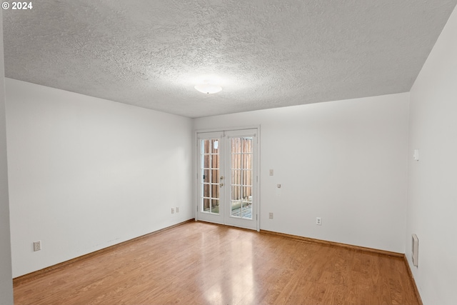 spare room with french doors, a textured ceiling, and hardwood / wood-style flooring