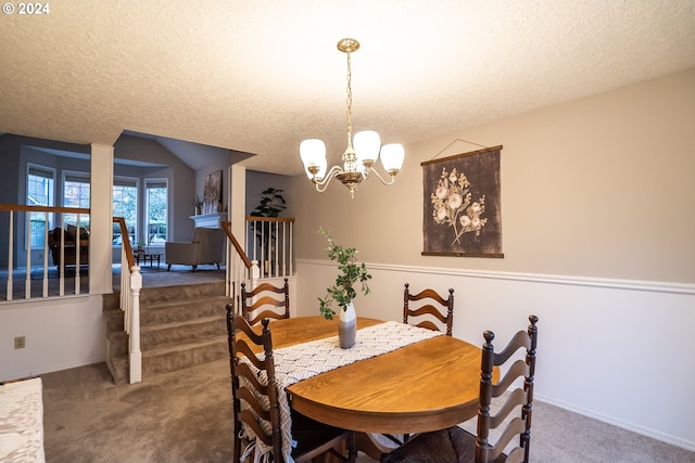 dining room featuring carpet, a chandelier, and a textured ceiling