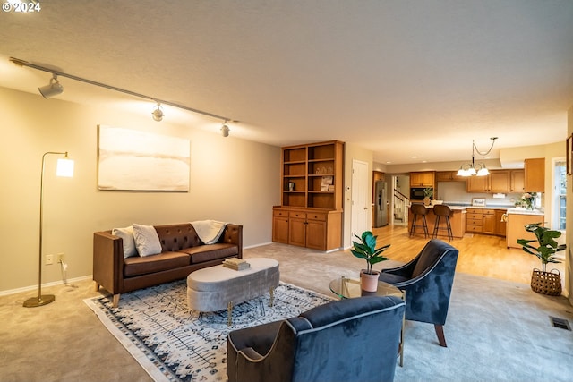 living room featuring a notable chandelier, light colored carpet, and track lighting