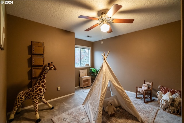 recreation room with carpet flooring, ceiling fan, and a textured ceiling