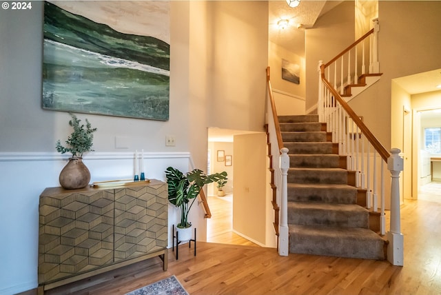 stairway featuring wood-type flooring and a high ceiling