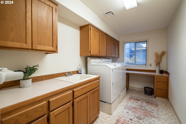 laundry area with washing machine and dryer, sink, cabinets, and a textured ceiling