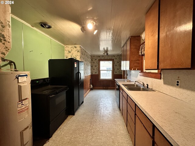 kitchen featuring wallpapered walls, electric water heater, a wainscoted wall, black appliances, and a sink