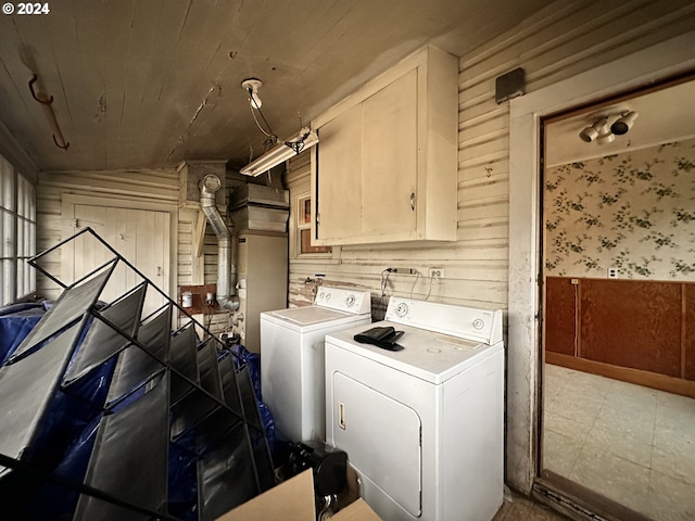 laundry area with cabinets, wooden walls, and independent washer and dryer