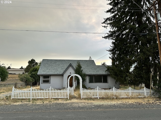 view of front of house with a fenced front yard and a shingled roof