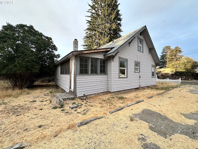 view of side of home featuring a chimney and fence