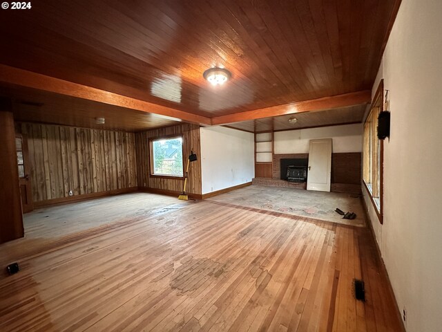 interior space with light hardwood / wood-style flooring, wood ceiling, and a brick fireplace