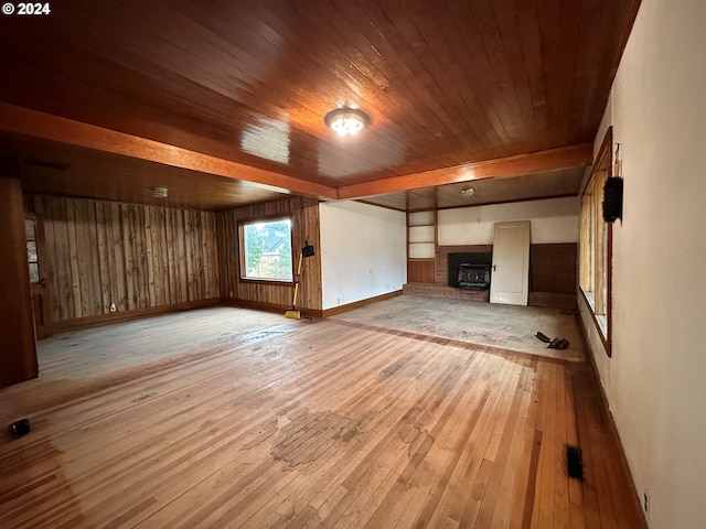 unfurnished living room with a brick fireplace, light wood-style flooring, baseboards, and wooden ceiling