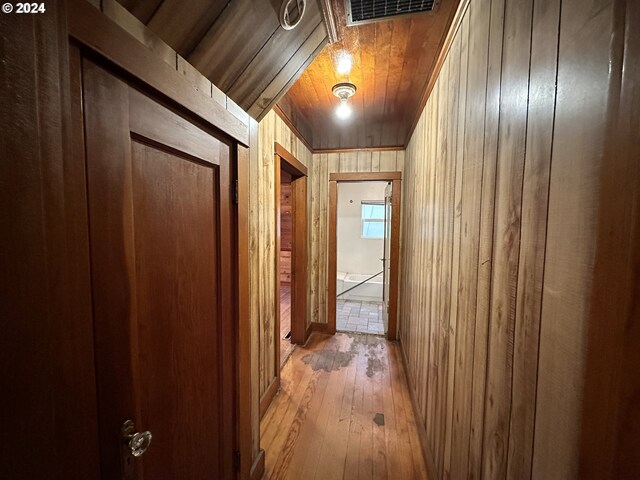 hallway featuring hardwood / wood-style flooring and wooden walls