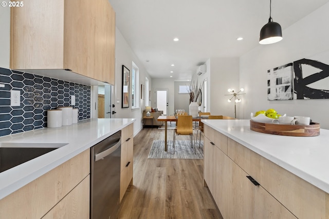 kitchen with light wood-style flooring, light countertops, dishwasher, light brown cabinetry, and decorative light fixtures