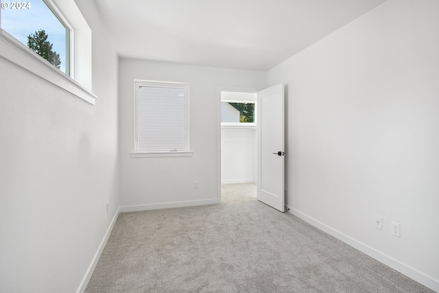 spare room featuring light colored carpet and baseboards