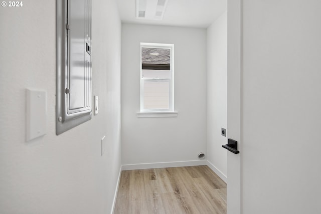 laundry room featuring baseboards, electric dryer hookup, and light wood finished floors