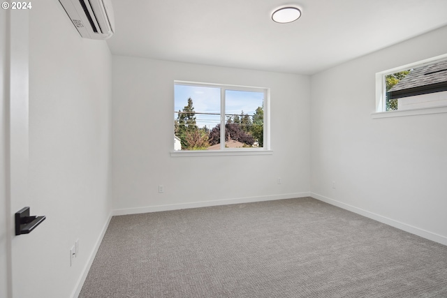 carpeted spare room with a wall unit AC, plenty of natural light, and baseboards