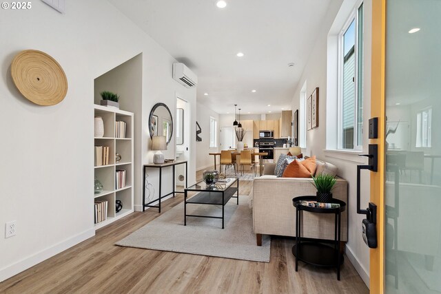 hall with light hardwood / wood-style floors and an AC wall unit