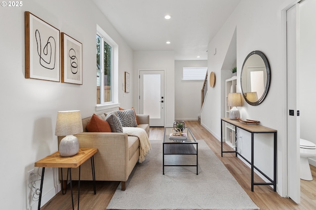 living area with baseboards, light wood finished floors, and recessed lighting