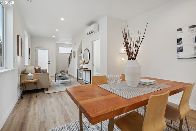 dining space featuring recessed lighting, an AC wall unit, baseboards, and light wood finished floors