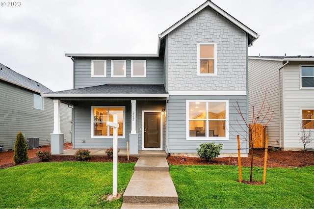 view of front of house with a porch, central AC unit, and a front lawn